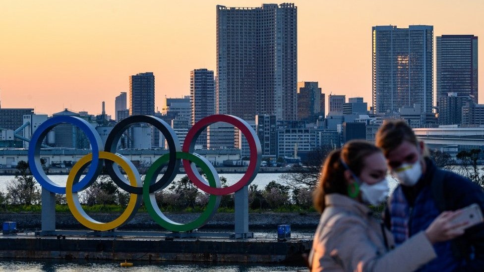 A couple takes a picture in front of the Olympic rings in Tokyo