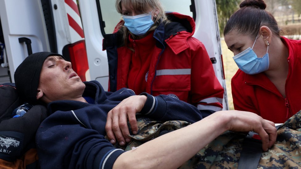 A man wounded in this morning's air strikes at a nearby military complex is assisted by medical staff outside Novoiavorivsk District Hospital on March 13, 2022 in Novoiavorivsk