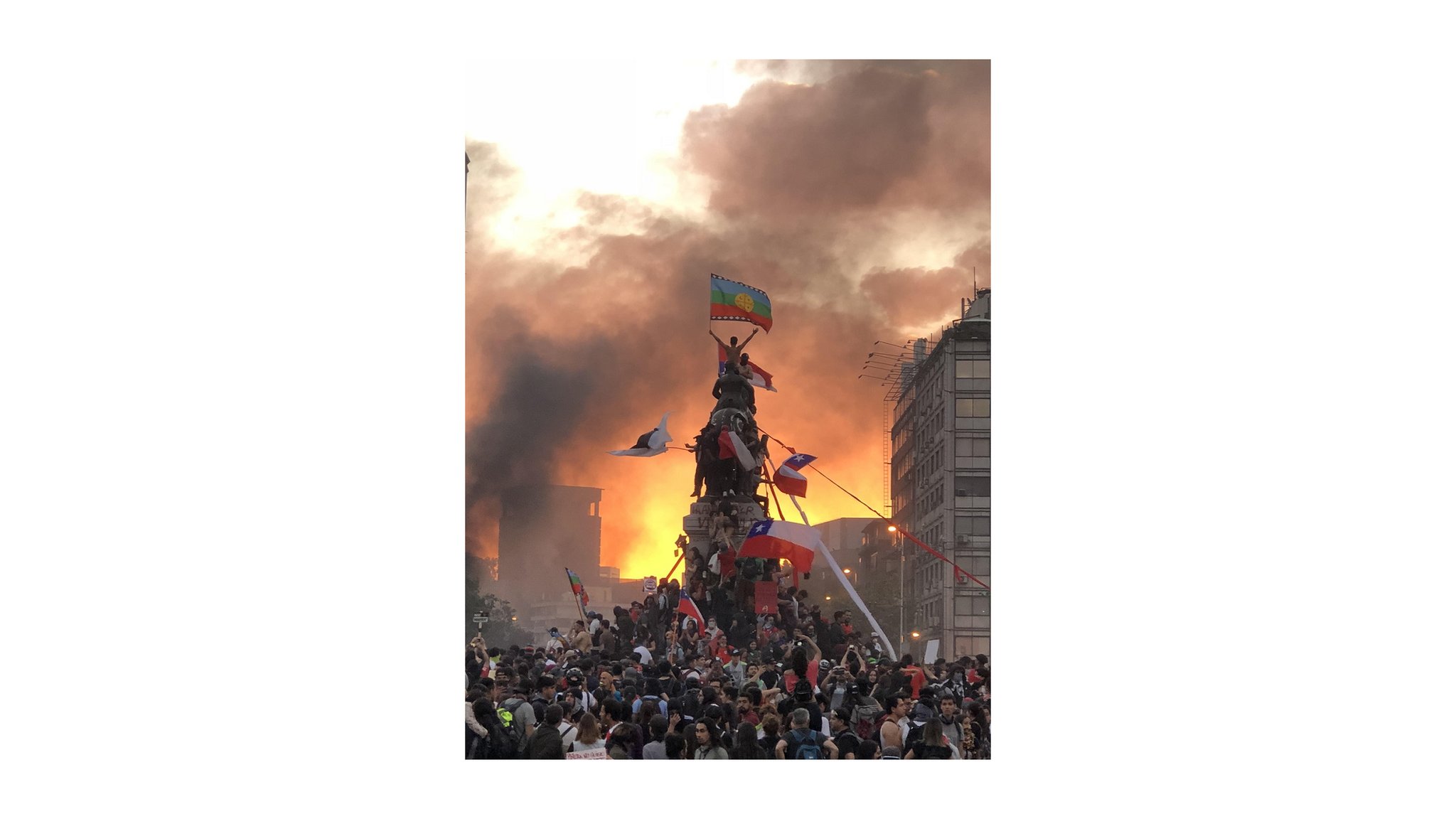 La imagen de un manifestante flameando la bandera mapuche en la cima de una estatua militar, en Santiago