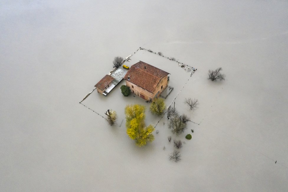 An aerial view of a house surrounded by flood water in the Po Valley