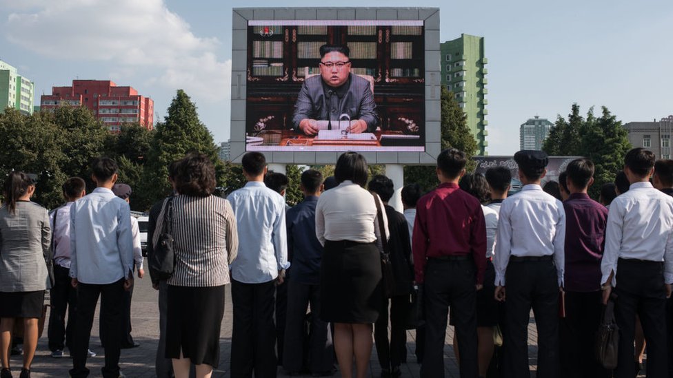 Gente viendo a Kim Jong-un en una pantalla