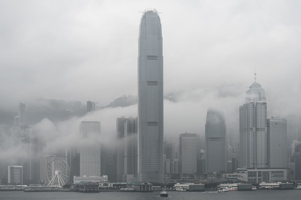 The International Finance Центральная башня (C) и городской пейзаж окутаны туманом в Гонконге 9 марта 2016 г.