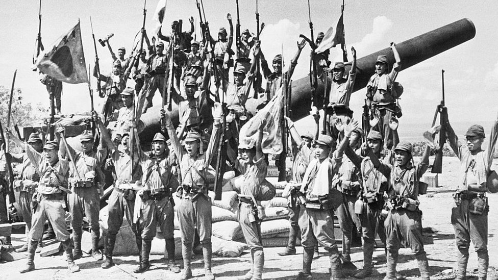 Japanese soldiers celebrate the capture of an American cannon in the Philippines.