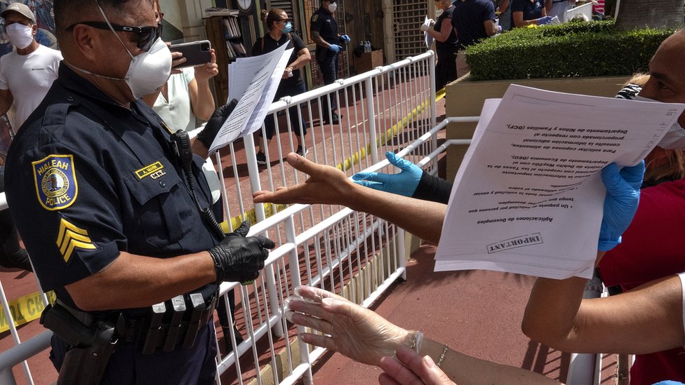 Офицер полиции раздает заявления на пособие по безработице на автостоянке во Флориде