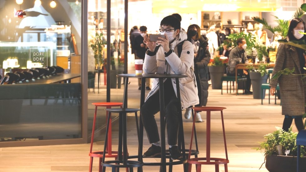 Мужчина пользуется мобильным телефоном в торговом центре Сеула - 2 декабря