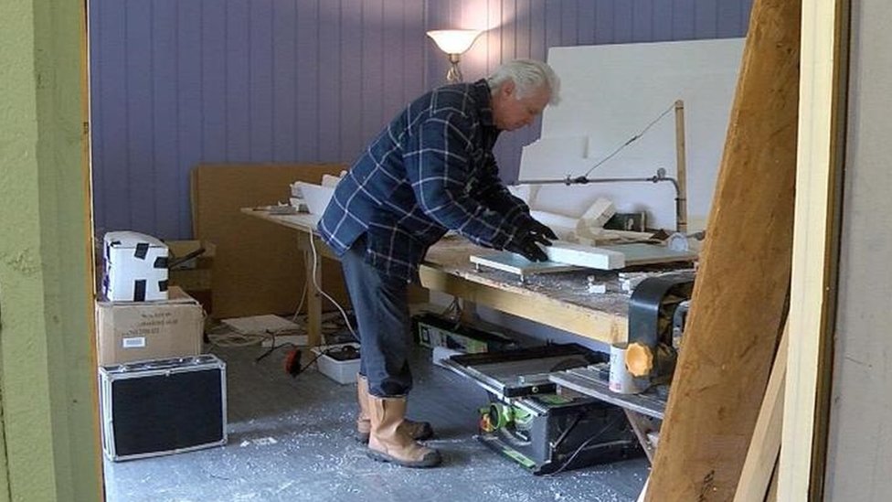 Мужчина режет пенопласт в своей мастерской.