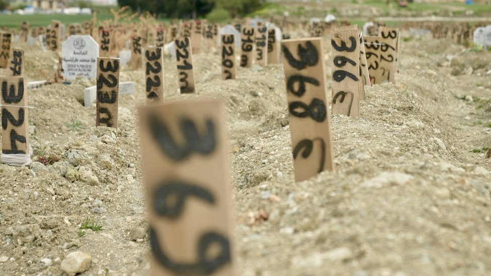 Rows of anonymous graves with makeshift, numbered markers where victims of the quake are buried