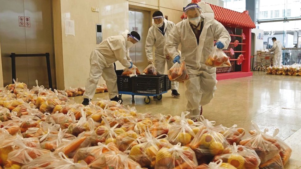 Trabajadores transportan suministros a un almacén temporal en un campo de fútbol en Shanghái el 5 de abril de 2022.