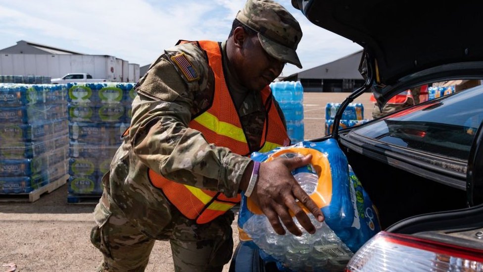 Un militar carga una caja de agua potable para repartir en misisipi