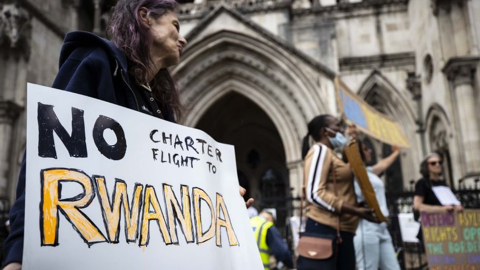 Personas con pancartas en contra del plan del gobierno británico de enviar solicitantes de asilo a Ruans