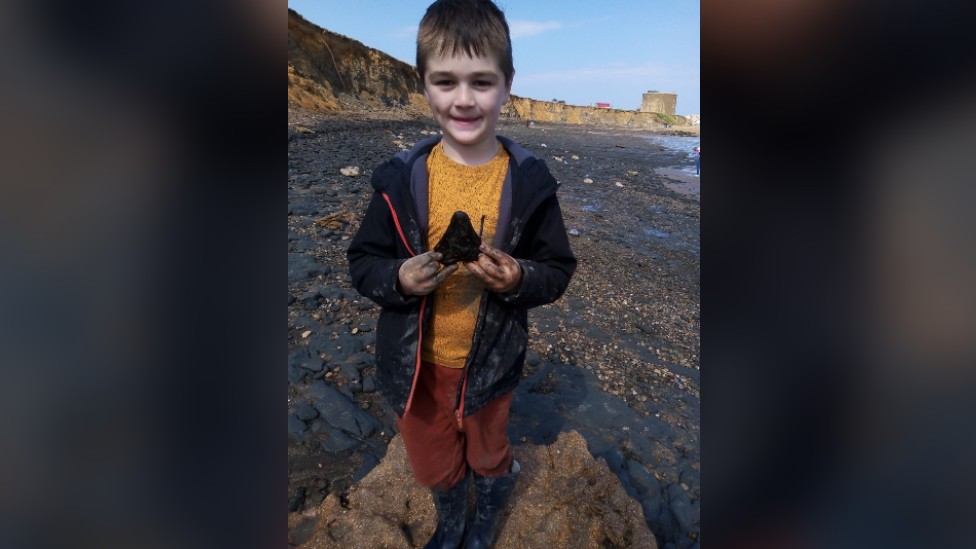 Sammy Shelton with the tooth he found on the beach in his hands.