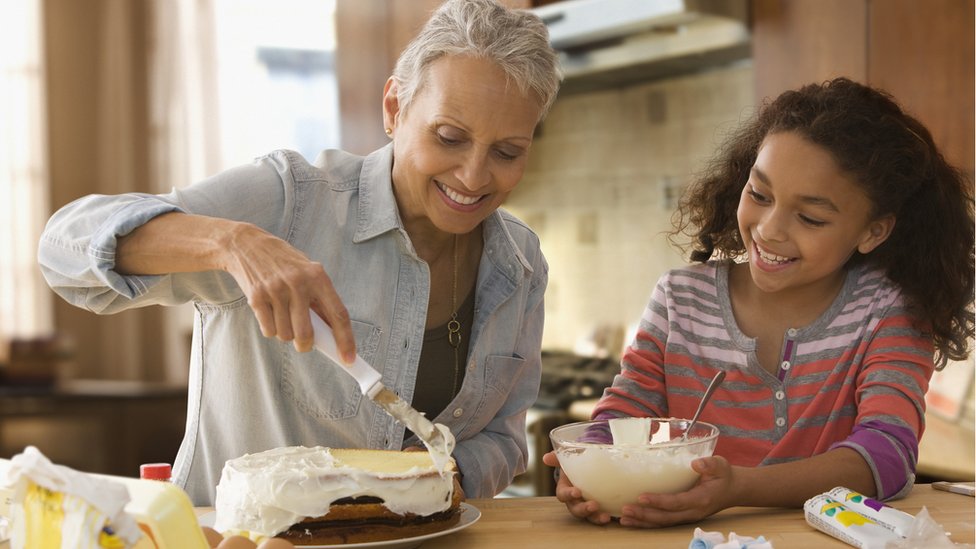 Mãe e filha confeitando bolo juntas