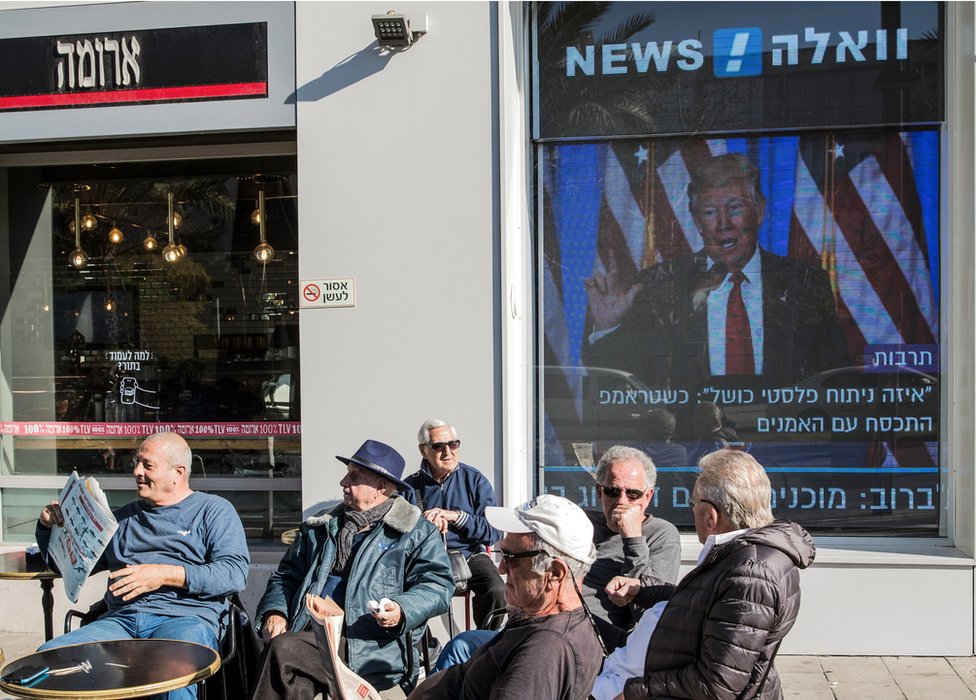 Café en Israel con pantalla con Trump de fondo.