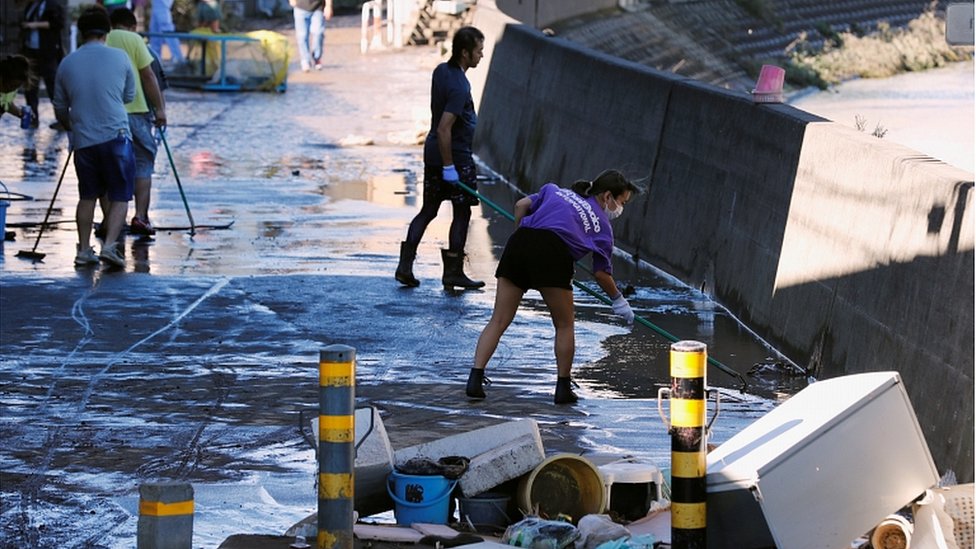 Люди убирают мусор после того, как паводок, вызванный тайфуном «Хагибис», отступил в жилом районе в Кавасаки, Япония, 13 октября 2019 г.