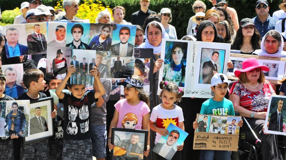 Yazidi children in Canada hold photos of family members killed by ISIS