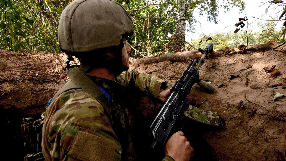 Ukrainian soldier stands watch at a river observation post