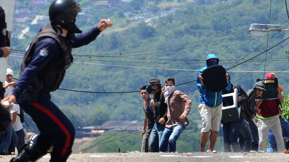 Член ОМОНа бросает бомбу со слезоточивым газом во время акции протеста студентов, выступающих против правительства Николаса Мадуро, в Сан-Кристобале, штат Тачира, Венесуэла, 24 октября 2016 г.