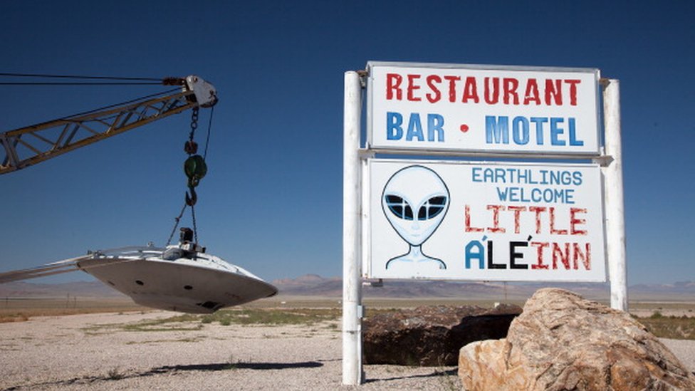 Sign for Little A'Le'Inn and flying saucer hanging from tow truck, Rachel, Nevada