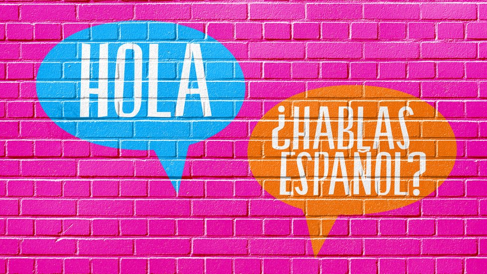 Hola y ¿Hablas español? escritos en una pared.