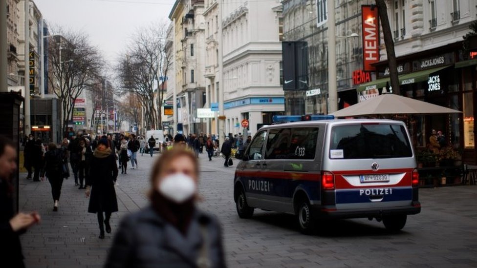 A police car is seen as pedestrians walk along a shopping street after the Austrian government placed roughly two million people who are not fully vaccinated against the coronavirus disease (COVID-19) in lockdown