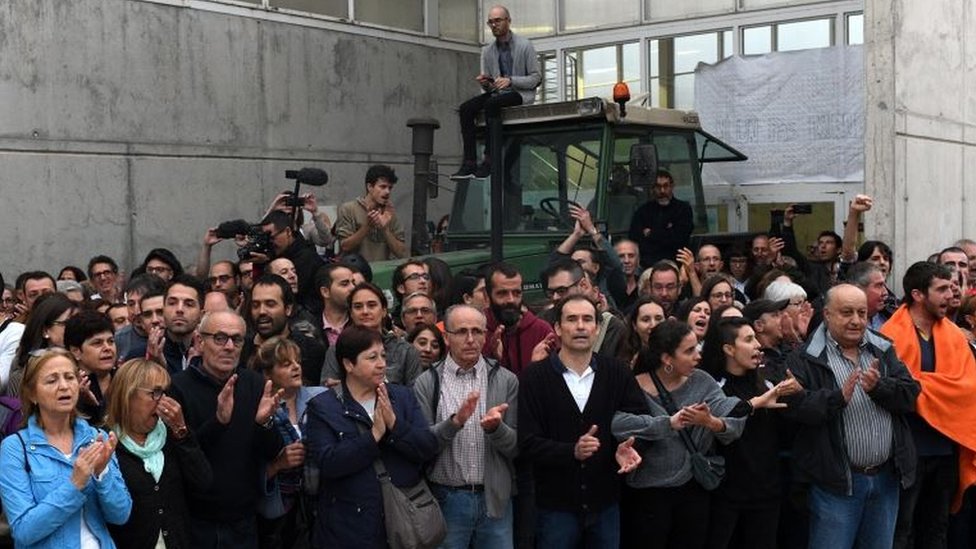Un grupo de catalanes en Sant Julia de Ramis se concentraron afuera de un centro de votación para evitar que la policía española entre. Un portavoz del gobierno regional catalán, Raúl Romeva, dijo estar confiado en que muchas personas podrán votar a pesar de que la policía nacional española había confiscado nueve millones de papeletas y otros materiales de votación y había detenido a los organizadores de la consulta. Grupo de votantes