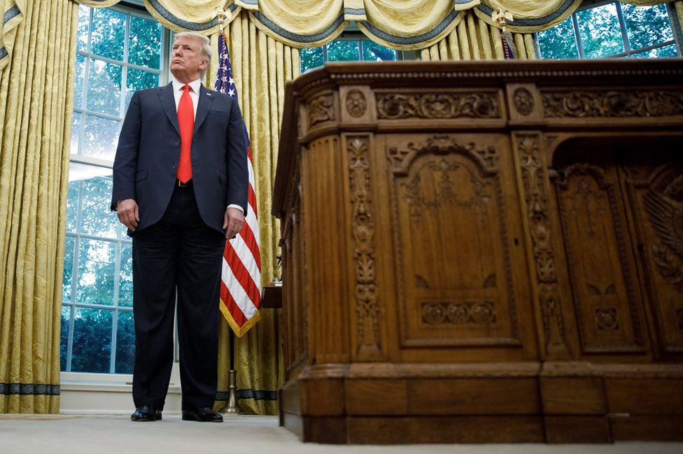 Дональд Трамп стоит в Овальном кабинете