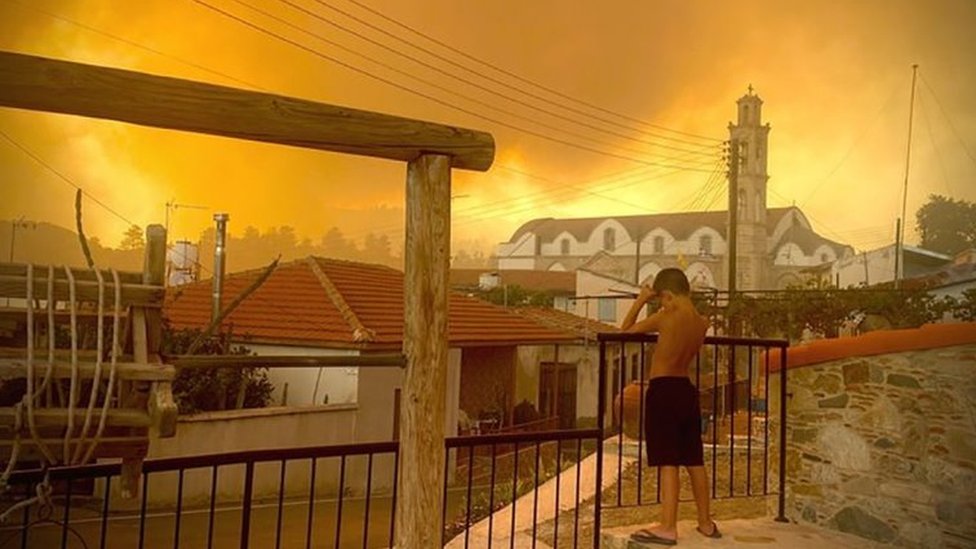 A child in Ora village, near Larnaca, looks as smoke rises from a wildfire. Photo: 3 July 2021