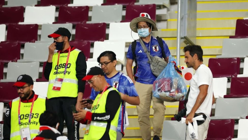 Japan fans holding bags full of rubbish with security