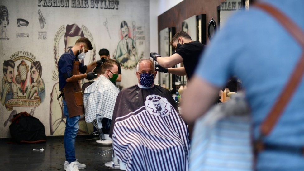 Парикмахеры в масках стригут клиентам волосы в салоне в Дортмунде, Германия