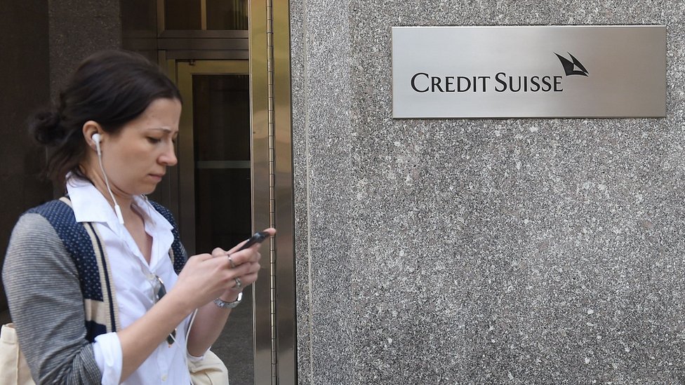 Mujer pasa delante de la fachada de una sucursal del banco Credit Suisse.