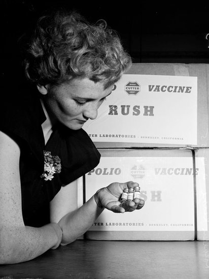 Una mujer sosteniendo frascos de la vacuna contra la polio de los laboratorios Cutter.