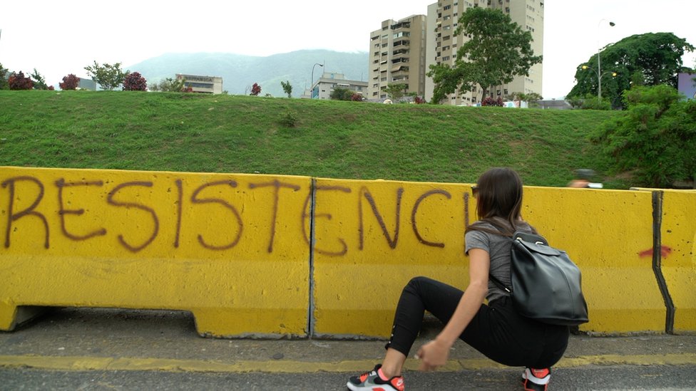 Женщина прячется за баррикадой со словом «сопротивление»