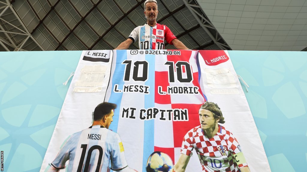 مشجع يرتدي قميص ويحمل علم نصفه من قميض ميسي والنصف الآخر من قمي مودريتش قبل مباراة دور الـ16 بين اليابان وكرواتيا.