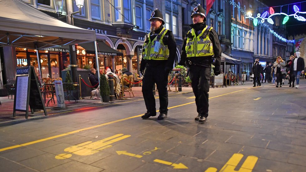 Двое полицейских Южного Уэльса в форме и шлемах патрулируют барную зону в центре Кардиффа после того, как в ноябре закончилась изоляция от пожаров и объекты были вновь открыты