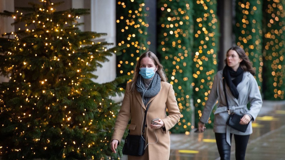 People walk past Christmas lights outside a closed shop on Oxford Street, London.