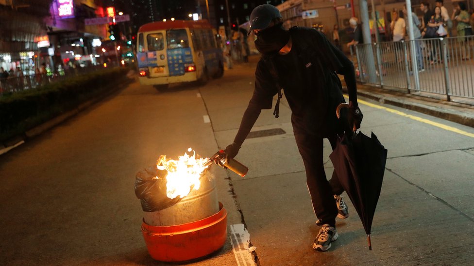 Un manifestante prende fuego a un cesto de la basura.