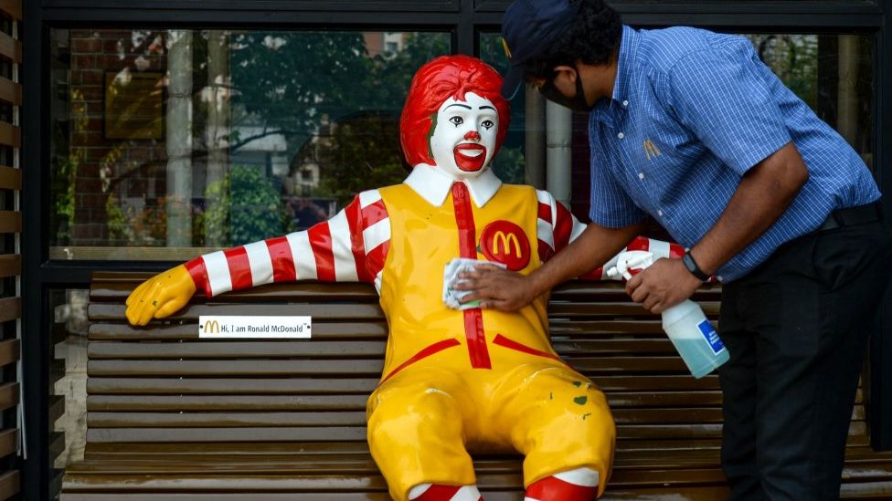Рабочий убирает талисман компании быстрого питания McDonald's к открытию торговой точки в Хайдарабаде 20 мая.