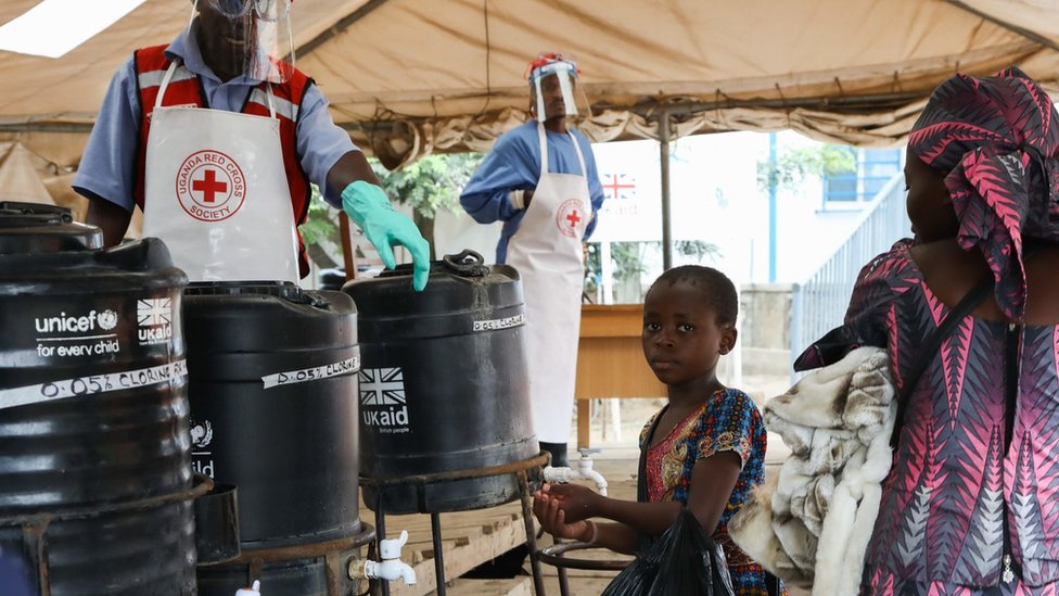 Молодая девушка моет руки на контрольно-пропускном пункте по профилактике Эболы при поддержке Великобритании на пункте пересечения границы Уганды с ДРК, август 2019 г.