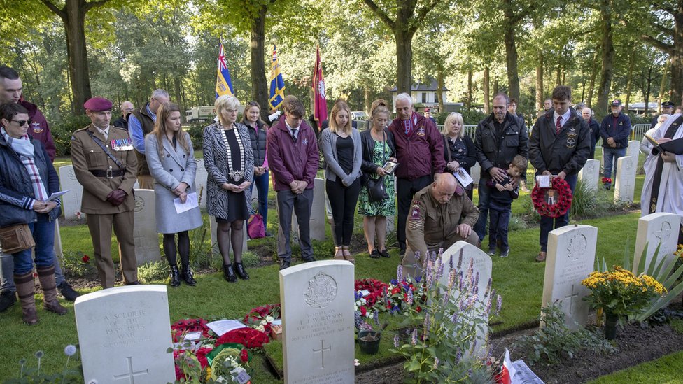 Семья и друзья Денниса Коллиера посещают службу по погребению праха на военном кладбище CWGC Oosterbeek недалеко от Арнема, Нидерланды.
