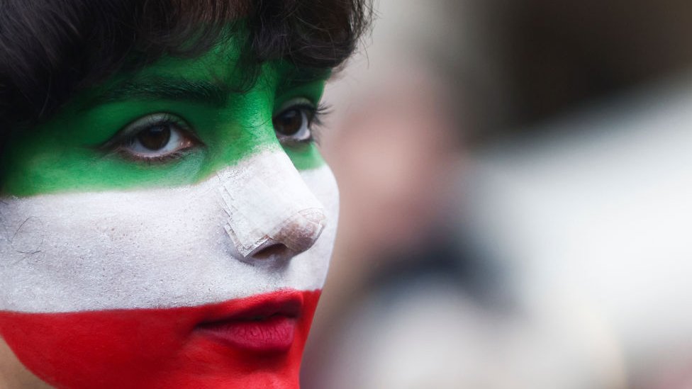 Mujer con el rostro pintado con los colores de la bandera iraní en Polonia.