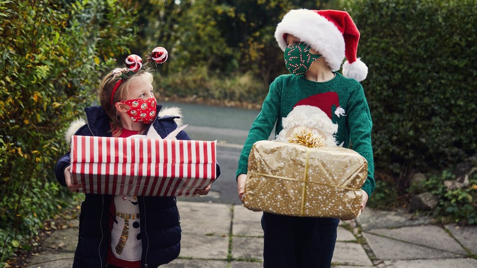 Children with Christmas presents and face coverings