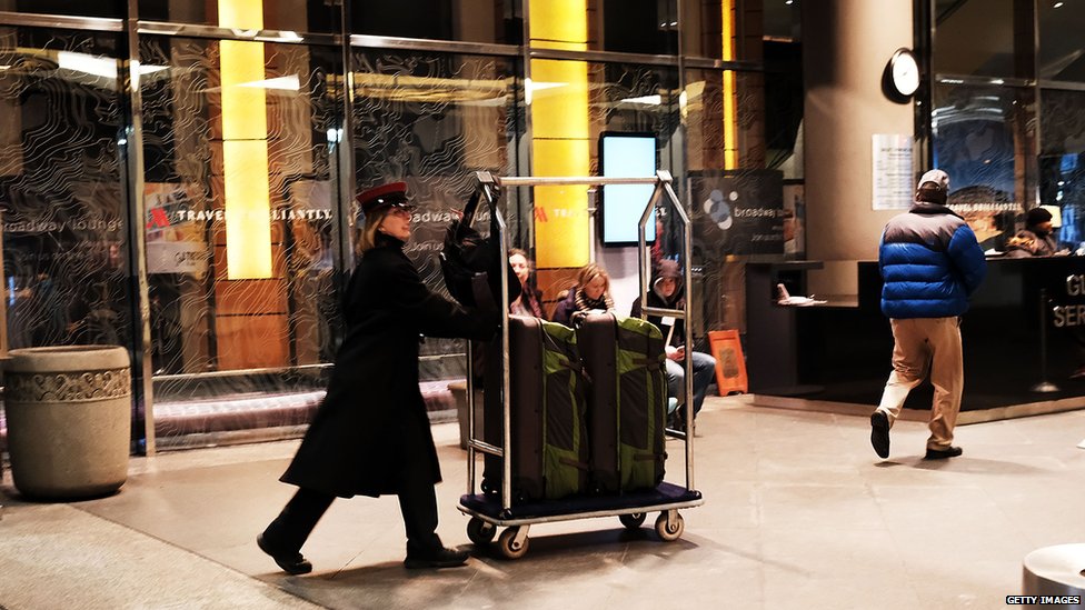 Сотрудник отеля Marriott в центре Манхэттена переносит сумки гостей