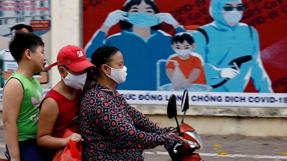 A woman wears a protective mask as she drives past a banner promoting prevention against the coronavirus disease (COVID-19) in Hanoi, Vietnam July 31, 2020.