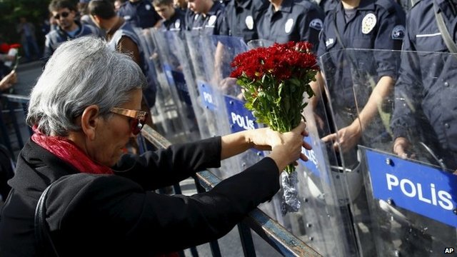 A demonstrator holds flowers before a police barricade during a commemoration for the victims of Saturday's bomb blasts in the Turkish capital, in Ankara, Turkey, 11 October 2015