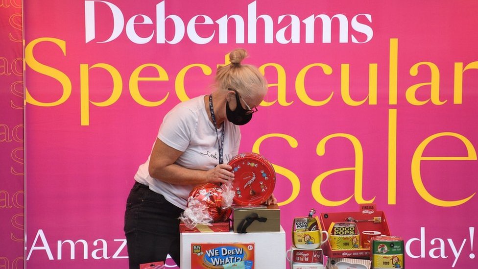 Продавец настраивает витрину в Debenhams перед вывеской о распродаже