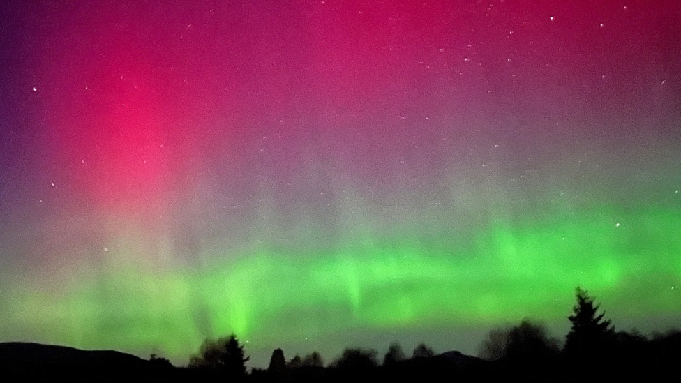 Cahaya hijau terang dan merah pekat memenuhi langit di Dataran Tinggi Skotlandia.