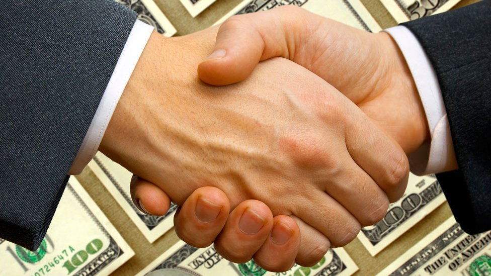 Dos hombres se dan la mano con un fondo de dólares