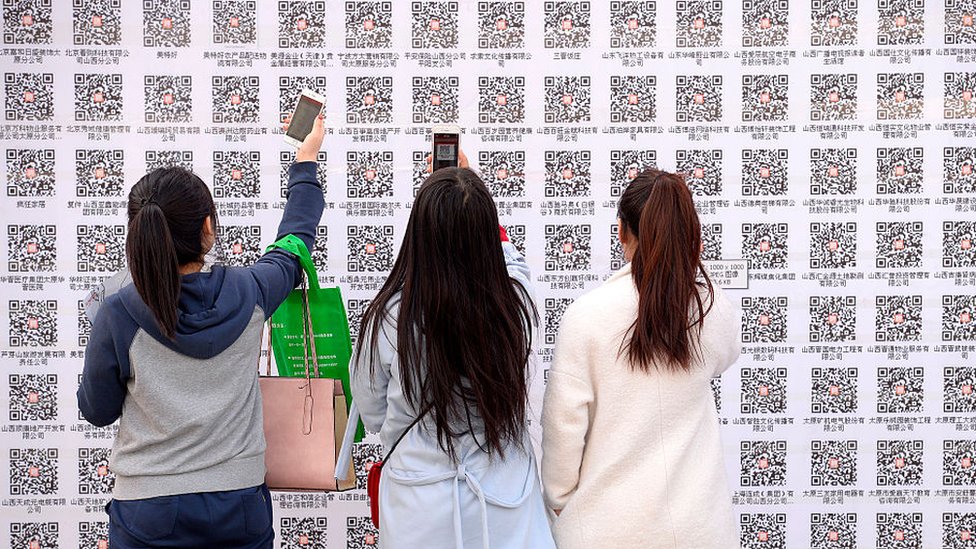 Su sistema de pagos a través del celular es una de las calves de su éxito. jóvenes leyendo un código QR a través de su teléfono móvil.