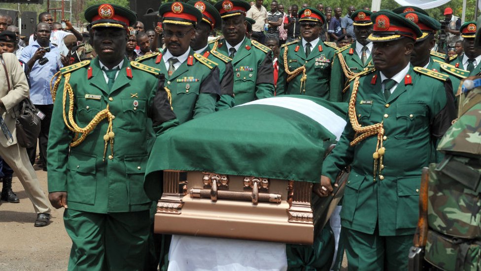 Бронзовая шкатулка с телом Одумегву Оджукву несут в его родной дом Нневи армейские гроба после национальных межконфессиональных похоронных обрядов