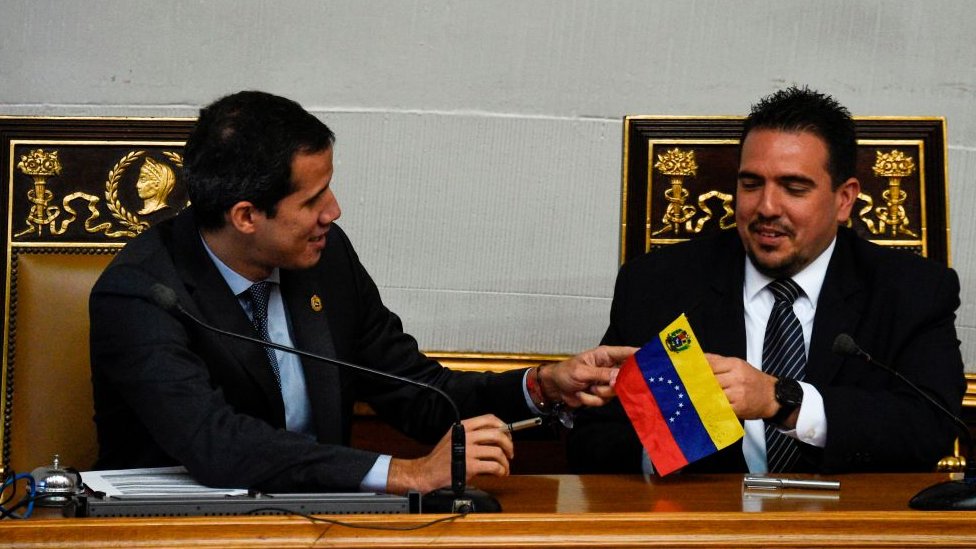 El diputado Stalin González (der.) recibe una pequeña bandera de Venezuela de manos de Juan Guaidó.